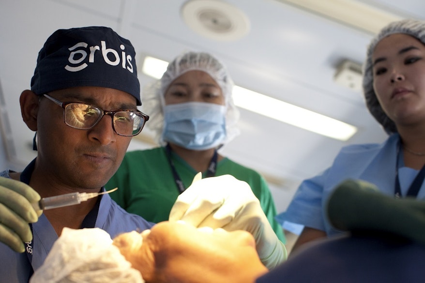 Sudheer Sukumar providing treatment to a patient, colleagues in scrubs behind him